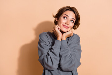 Photo portrait of lovely young lady look dreamy touch cheeks fists wear trendy gray garment isolated on beige color background