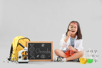 Cute little girl scientific equipment and chalkboard with text CHEMISTRY on grey background