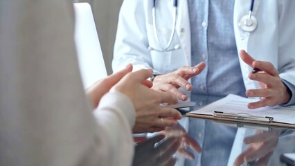 Doctor man and woman patient are discussing something and gesturing with their hands in medical office, close up. Medicine concept