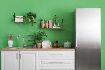Interior of kitchen with silver fridge, counters and shelves