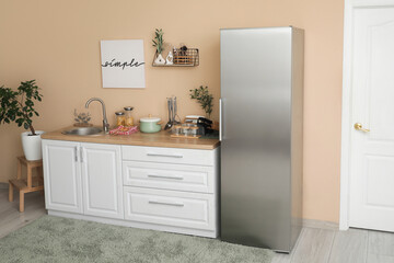 Interior of kitchen with silver fridge, counters and shelf