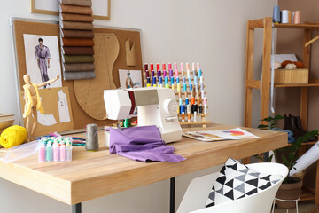 Fashion designer's workplace with sewing machine, thread spools and pin board in studio