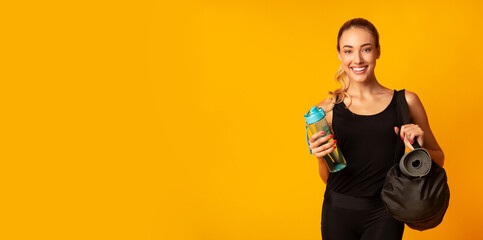 Woman Holding Fitness Bag, Rolling Mat And Water Ready For Training. Yellow Background, Studio...