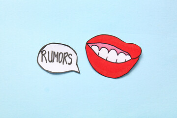 Paper mouth and speech bubble with word RUMORS on blue background. Gossip concept