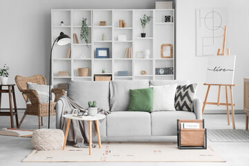 Interior of stylish modern living room with grey sofa, coffee table and shelving unit