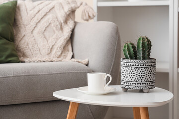 Cup of tea with cactus on coffee table in room, closeup