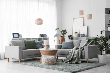 Interior of stylish modern living room with grey sofas, shelving unit and houseplants