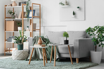 Interior of stylish modern living room with grey sofa, shelving unit and coffee tables