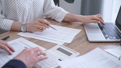 Fototapeta premium Bookkeeper woman is working with a colleague, using magnificent glass, calculator and laptop. Audit and taxes concept
