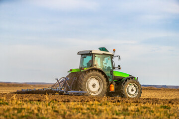 Obraz premium A tractor with plow in action, turning over the soil on a sunny day