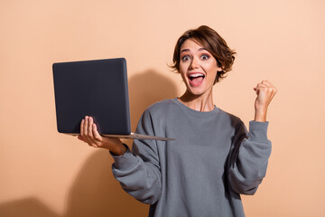 Portrait of satisfied crazy girl with short hairdo wear oversize pullover hold laptop yell win bet...