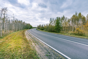 A road with trees in the background and a cloudy sky