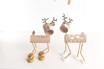 Toilet paper roll craft concept for kid and kindergarten DIY tutorial showing Christmas deer toy made from recycled materials. Fun recycle art project for kids with cardboard tubes and bottle caps,