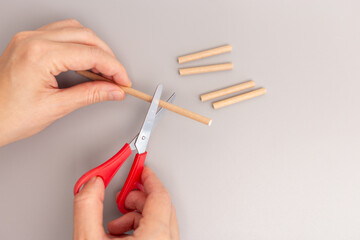 a close up of a hand holding a pair of scissors cutting paper straw, step in creative process, DIY,...