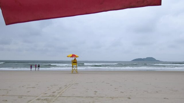 Cloudy morning at Tombo beach. Beach of Guaruja, SP, Brazil. View to the beach, the lifeguard and some people.