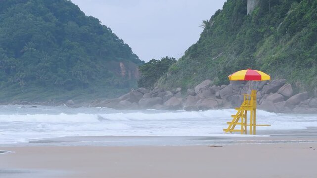 Rough sea at the Tombo beach of Guaruja - SP, Brazil. Beach of the coast of S&atilde;o Paulo state. View to the beach, the lifeguard chair and some mountains on background.