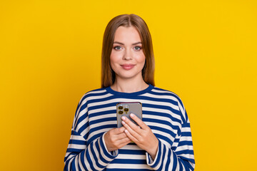Photo of nice cute woman wear striped stylish clothes use iphone isolated on yellow color background