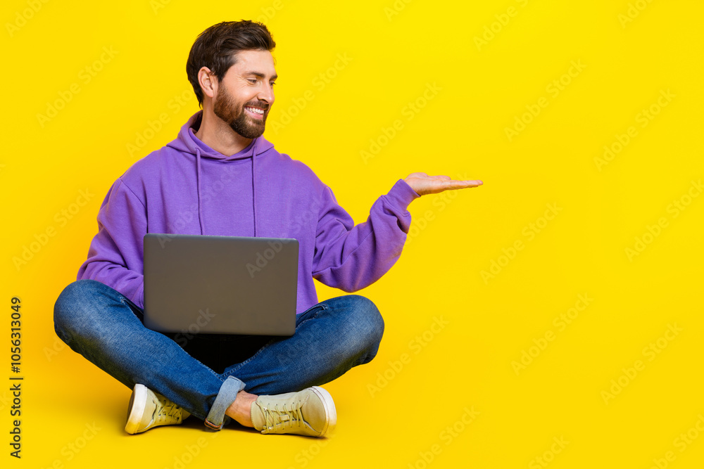 Poster full length photo of nice young male hold empty space netbook dressed stylish violet garment isolate