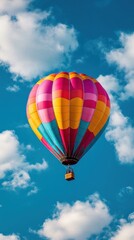 Fototapeta premium Colorful hot air balloon soaring through a clear blue sky with fluffy clouds.