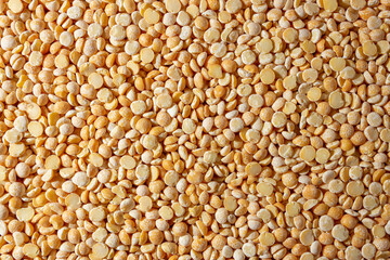 Uncooked Polished Split Peas Background. A Culinary Canvas of Dry Yellow Peas, Creating a Lively and Textured Background for Gourmet Cooking. Scattered Raw Polished Peas. Healthy Eating Ingredients