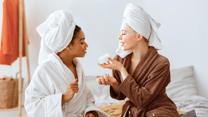 Sensual international spa girlfriends testing new body lotion, having beauty day at home, panorama