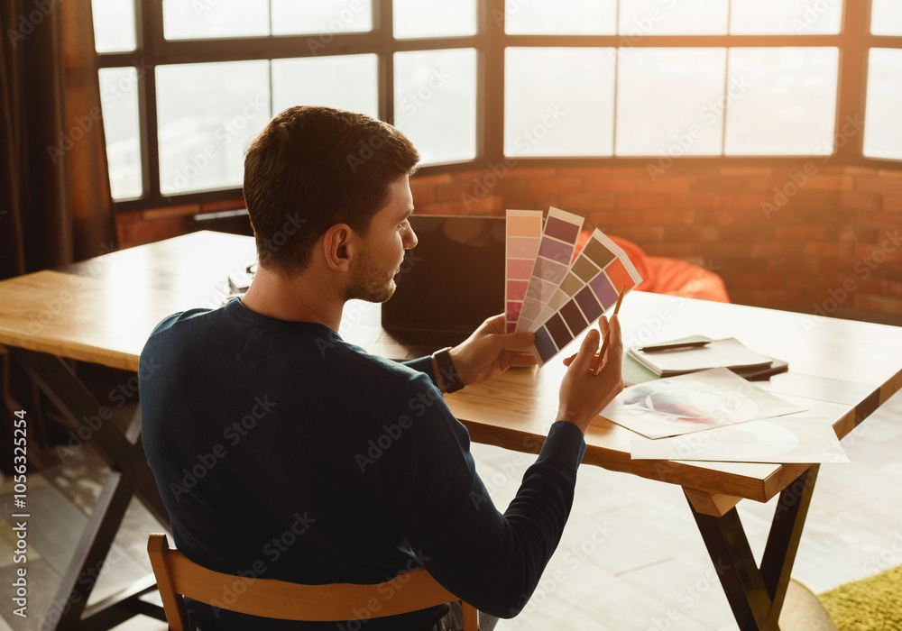 Poster professional designer at laptop working with color palettes and samples sitting in modern office. se