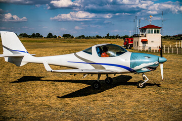 A small plane with a spinning propeller and a shark face painted on it