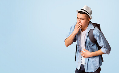 Young guy traveler having problems with digestive, holding belly and touching moth over orange studio background