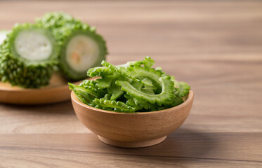 Sliced bitter gourd in bowl on wooden background, Food ingredient