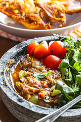 fried tilapia dip into chili dip with fresh lemon basil, tomato and shallot, sambal pecak indonesian dish