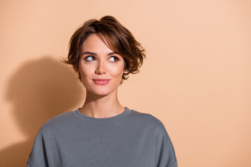 Photo portrait of lovely young lady look interested empty space dressed stylish gray garment isolated on beige color background
