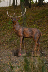 Wooden statue of a deer near the forest.
