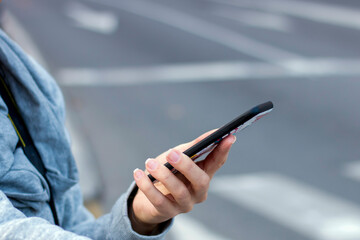 Woman texting on the smart phone walking in the street in a sunny day