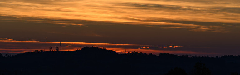 Orange sky with mast and hills in background.
