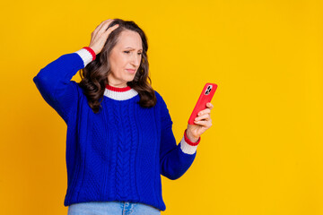 Photo portrait of lovely pensioner lady hold telephone stressed dressed stylish blue knitted garment isolated on yellow color background