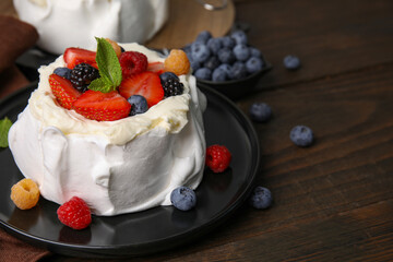 Pavlova cake (meringue dessert) with whipped cream, fresh berries and mint on wooden table, closeup