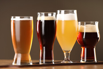 Glasses with different types of beer on wooden table indoors, closeup