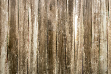 Worn and aged wood from exposure to sun and rain. The wood shows signs of chipped aging.  wood showing its rough textures and aged patterns, rustic charm.