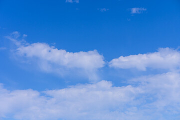 Bright blue sky filled with fluffy white clouds drifting peacefully on a sunny day