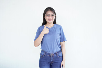 Beautiful Asian woman smiles warmly, giving a thumbs-up gesture to convey approval against a white...