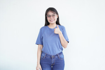 Beautiful Asian woman smiles warmly, giving a thumbs-up gesture to convey approval against a white...