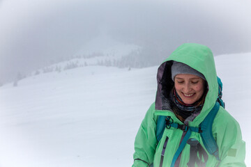 Snowflakes dance in the air as an outdoor enthusiast radiates joy, their lime-colored weatherproof jacket standing out against the white winter landscape.