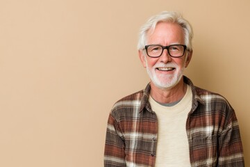 Senior male presenter, dressed casually, smiling, in front of a solid beige background with copy space