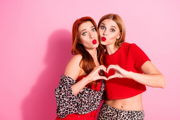 Photo of adorable lovely pretty girls wear trendy clothes demonstrating heart sign isolated on pink color background
