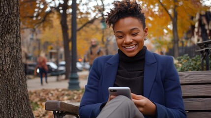 Fototapeta premium Smiling young woman using smartphone on a park bench, concept of digital connection and autumn tranquility