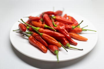 Fresh red chili peppers arranged on a white plate.