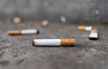 A close up of a discarded cigarette butt on pavement, emphasizing littering and pollution.
