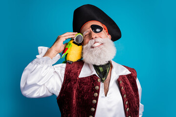 Photo portrait of senior funny pirate grandpa pet hugging parrot wear masquerade party costume...