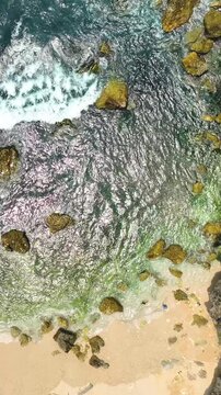 The hill is covered in moss and the beach is rocky with small pebbles. The scene is peaceful and serene