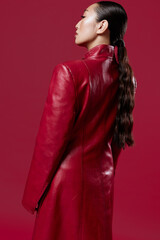 Fashion asian brunette woman in red leather coat looking into the distance with hair in a ponytail